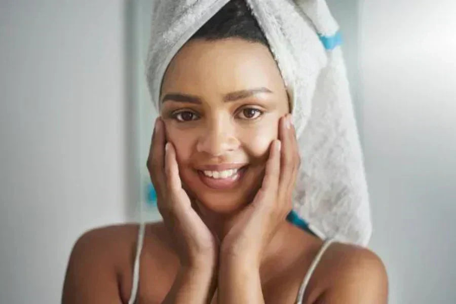 Woman with hair wrapped in a towel, touching her hands to her face