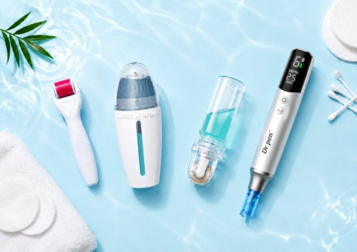 Flat lay of microneedling skincare tools, including a Dr. Pen microneedling pen, derma roller, derma stamp and serum applicator, arranged with cotton pads, cotton swabs and green leaves on a clean white and mint background.