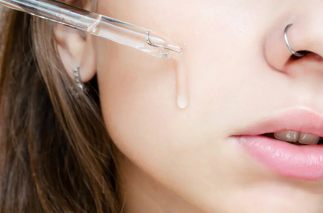 Close up of a young woman applying a hydrating skincare serum to a cleansed face