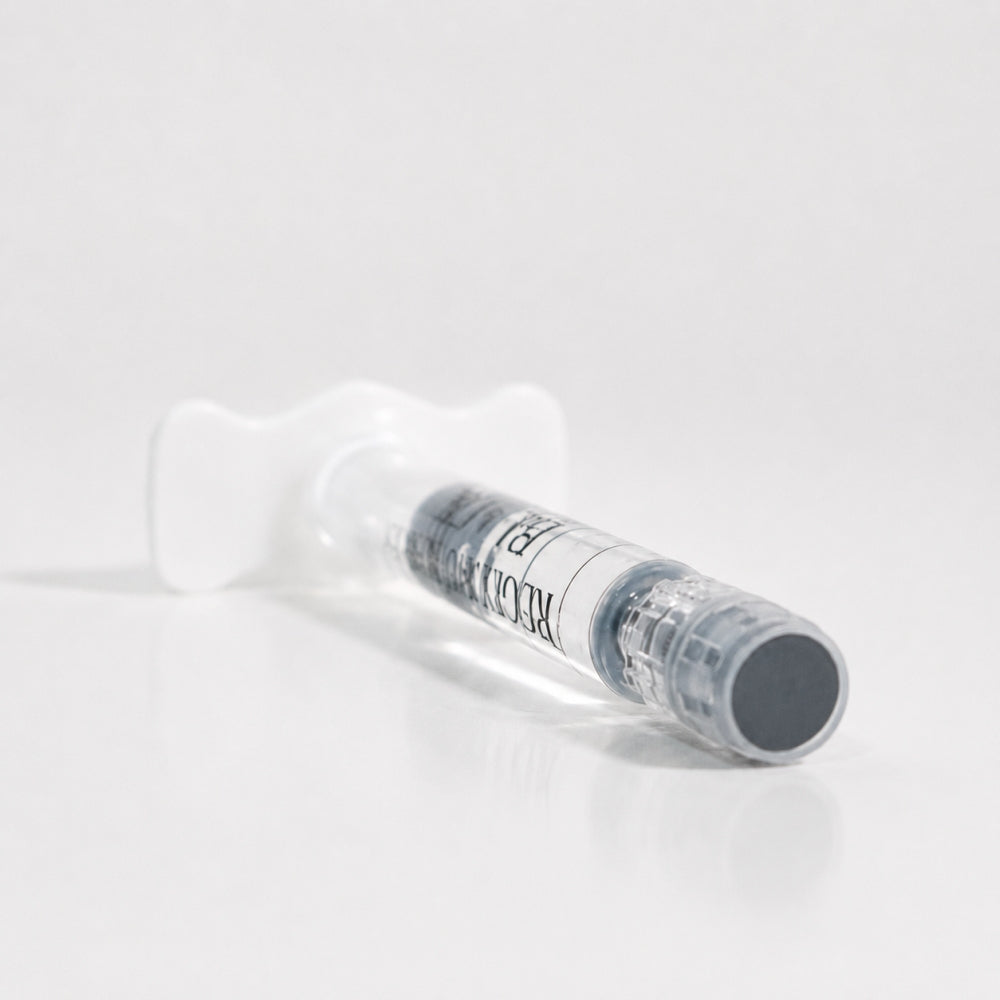 Close-up of Reglory Eyes Black PN 1% syringe lying on a white reflective surface